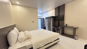 A modern hotel room with a bed, a desk, and a TV. - Gs 2 Syariah (Surakarta)