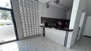 A modern reception area with a glass partition, a coffee station, and a counter. - Gs 2 Syariah (Surakarta)