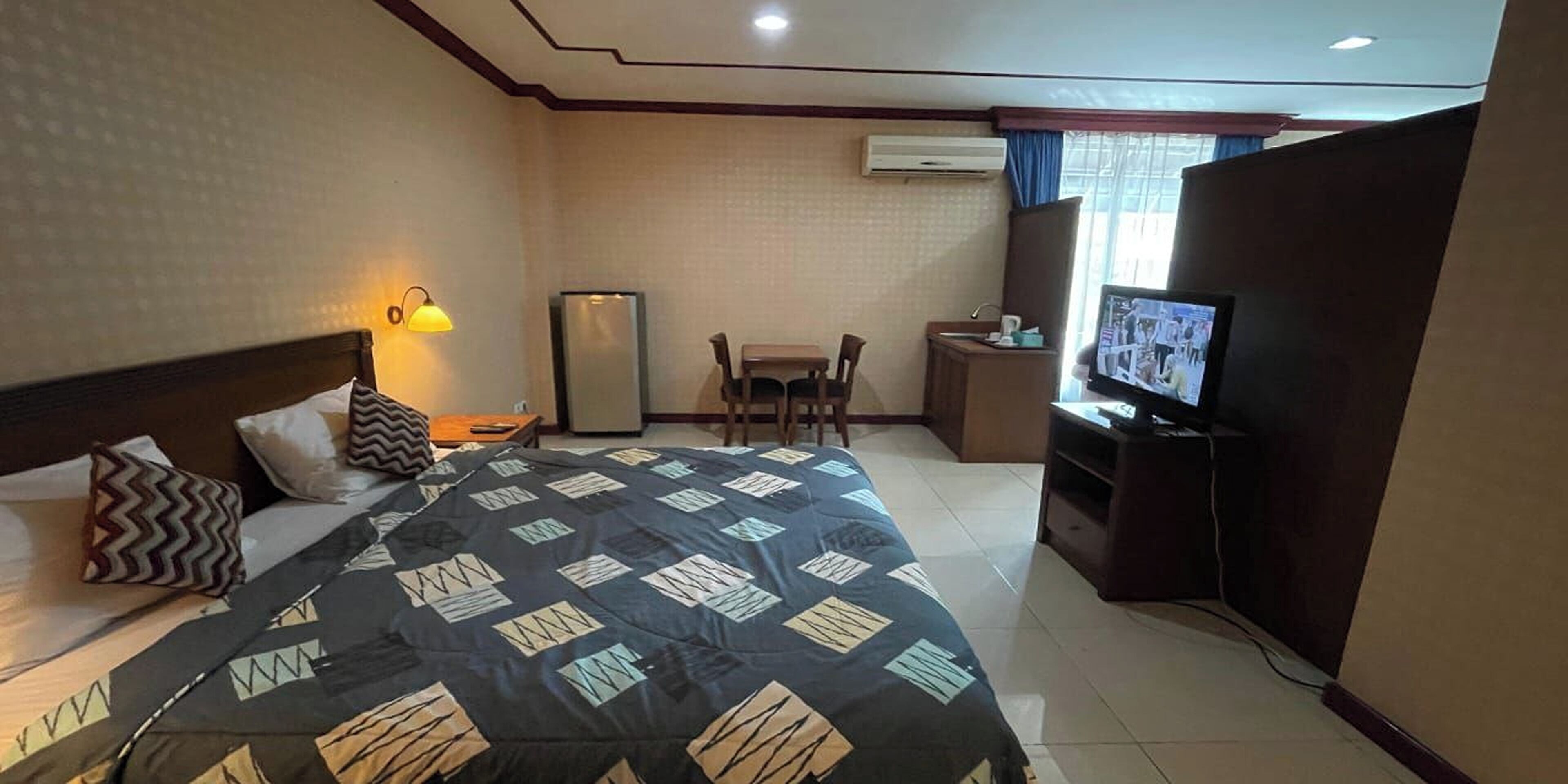 Ein Hotelzimmer mit Bett, Schreibtisch, Fernseher und Klimaanlage.
