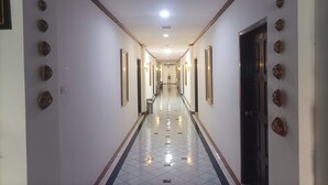 A long, narrow hotel corridor with a tiled floor, framed pictures on the walls, and a door at the end. - Hotel Efita (Bogor)