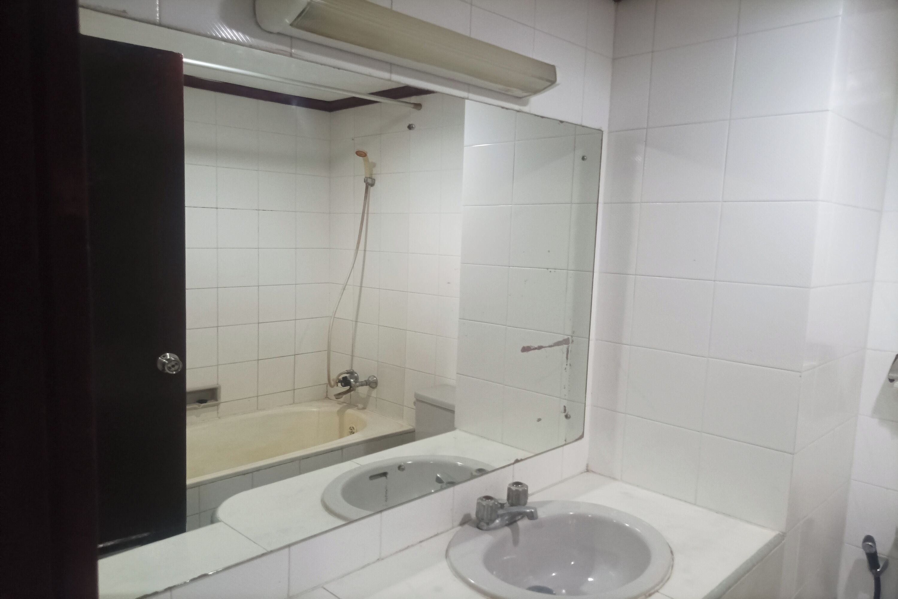 A bathroom with a large mirror, two sinks, a shower, and a toilet.