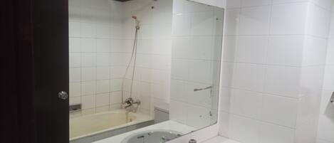 A bathroom with a large mirror, two sinks, a shower, and a toilet.