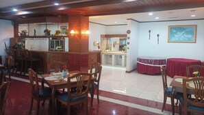 A restaurant with wooden tables and chairs, a counter with a display case, and a tiled floor. - Hotel Efita (Bogor)