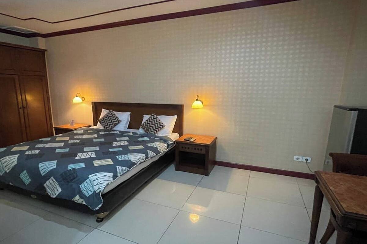 Une chambre d’hôtel comprenant un lit, des tables de chevet, une armoire et un bureau.