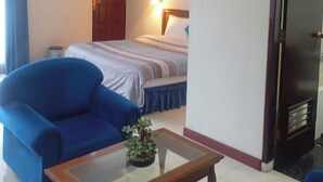 A hotel room with a bed, a blue sofa, a wooden coffee table, and a small potted plant. - Hotel Efita (Bogor)