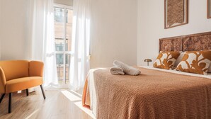 A hotel room with a bed, a chair, and a view through a window. - Pure Seville elegance and comfort (Sevilla)