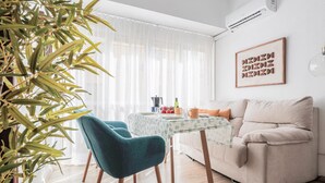A modern living room with a beige sofa, teal chairs, a wooden coffee table, and a large potted plant. - Pure Seville elegance and comfort (Sevilla)