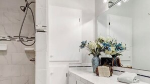 A modern bathroom with a white vanity, a large mirror, and a shower area. - Relaxing 3BR Family Retreat. Spacious • Peaceful • Close to everything (Peralta)