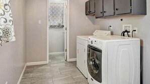 A laundry room with a washing machine, dryer, and gray cabinets. - Relaxing 3BR Family Retreat. Spacious • Peaceful • Close to everything (Peralta)