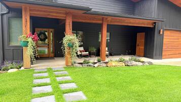 A modern house with a covered porch, stone pathway, and potted plants.