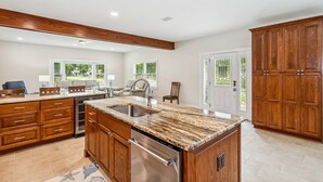 Un'ampia cucina con piani di lavoro in granito, mobili in legno e lavastoviglie integrata.