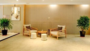 Un área de descanso moderna con dos sillones de mimbre, una mesa redonda y plantas en macetas.