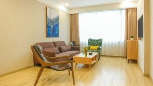 Una sala de estar con un sofá marrón, una mesa de centro de madera, un sillón verde y un cuadro en la pared.