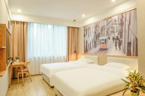 Ein Hotelzimmer mit zwei Betten, einem Esstisch mit Stühlen, einer Zimmerpflanze und einem großen Stadtbild-Wandgemälde.
