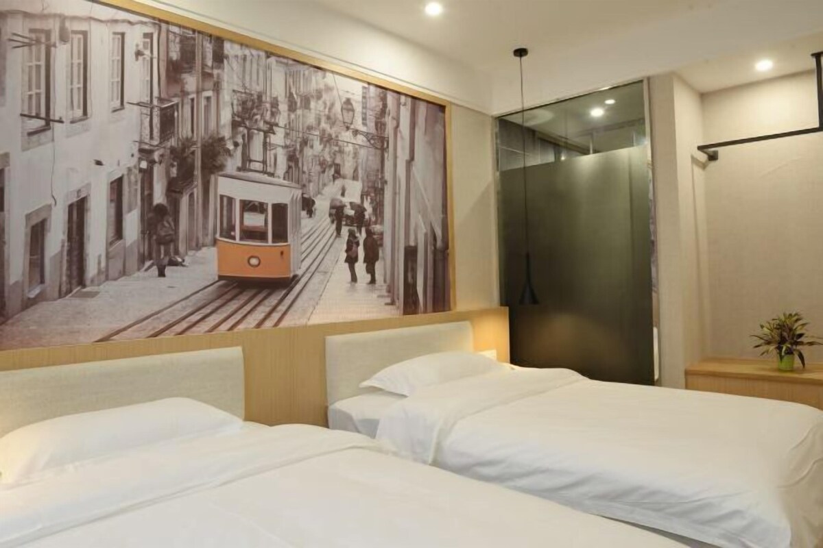Ein Hotelzimmer mit zwei Betten, einem großen Wandgemälde mit einem Straßenbahn und einem modernen Aufzug.