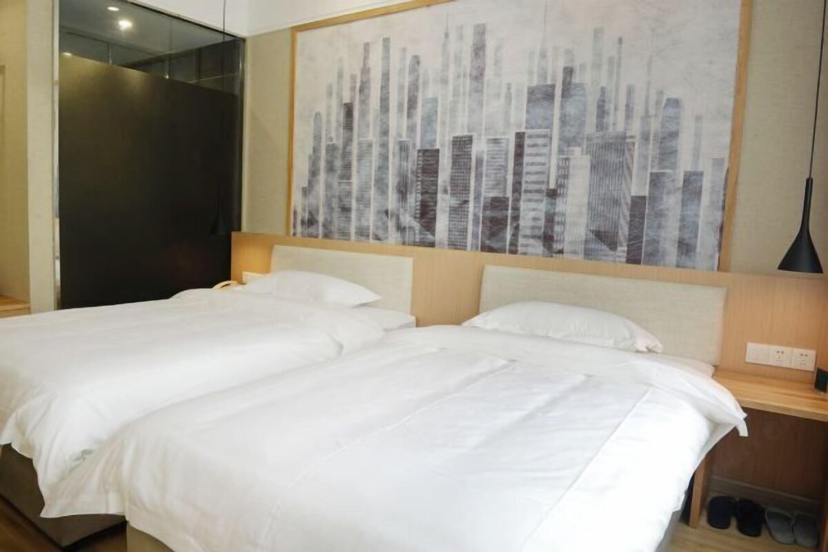 Ein Hotelzimmer mit zwei Betten, einem Stadtbild an der Wand und einem Schuhregal neben dem Bett.