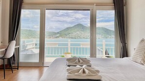 Een hotelkamer met een bed, een stoel en uitzicht op een meer en bergen.