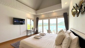 Een moderne slaapkamer met een groot bed, een bureau en een televisie aan de muur.