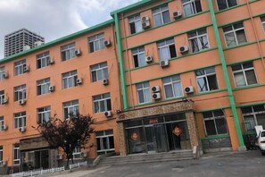 A multi-story building with a green and orange facade, multiple windows, and a visible entrance. - Xiaisi Lexiang Service Apartment (Dalian Xinghai Square) (Dalian)