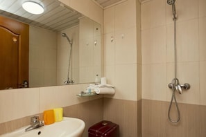 A bathroom with a sink, mirror, shower, and toilet.