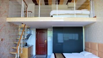 Una habitación con literas, un escritorio, una silla, una puerta y una ventana.