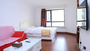 Une chambre d’hôtel avec un lit, un canapé, une table de chevet et un téléviseur.