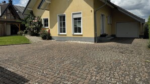 Une maison à deux étages avec un toit en pente, un garage et une allée pavée.