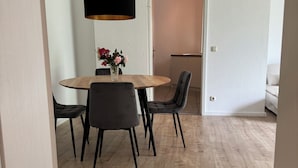 Un coin repas comprenant une table ronde en bois, quatre chaises, un vase avec des fleurs et une suspension.