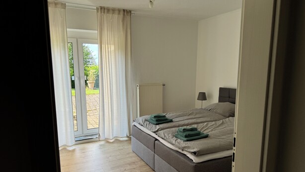 Une chambre avec un lit, un radiateur et une vue sur l’extérieur.