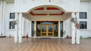 Fachada de edificio con suelo de baldosas, puertas de madera maciza y columnas.