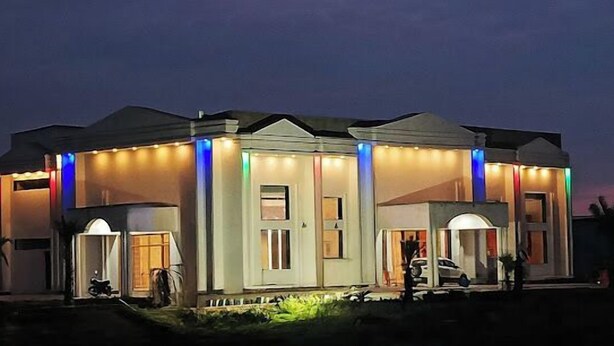 Un edificio moderno con entrada cubierta y varias ventanas, iluminado por luces de colores.