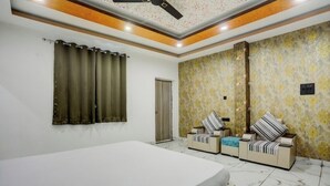Un dormitorio con una cama grande, dos sofás, un ventilador de techo y un papel tapiz estampado.