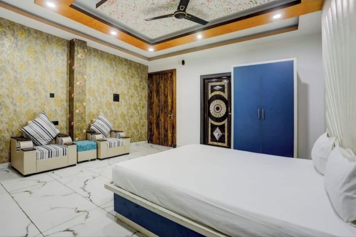Une chambre à coucher comprenant un lit, deux canapés, une armoire et un ventilateur de plafond.