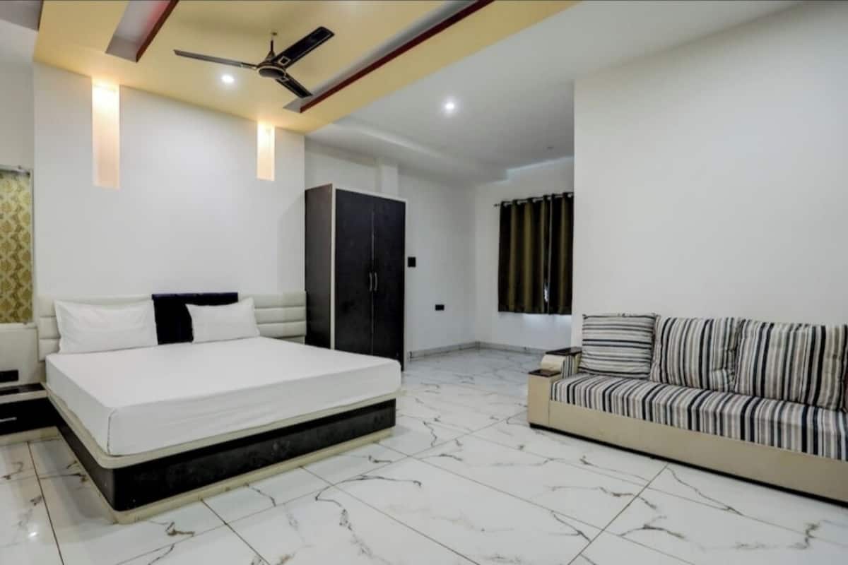 Une chambre à coucher comprenant un lit, un canapé, une armoire et un ventilateur de plafond.