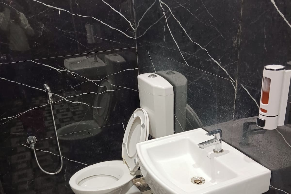 Une salle de bain comprenant des toilettes, un bidet et un lavabo. Le sol est recouvert de carreaux disposés selon un motif géométrique.