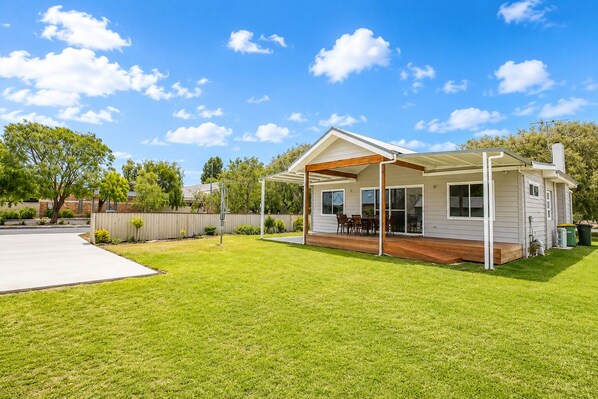 A single-story house with a covered patio, a lawn, and a fence.