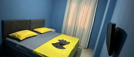 Un dormitorio con cama, cortinas y ventilador de techo.