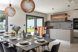 Een moderne keuken met een centraal eiland, ingebouwde houten kastjes en hanglampen.