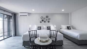 A modern hotel room with a large bed, a smaller bed, a dining table with chairs, and a large window.