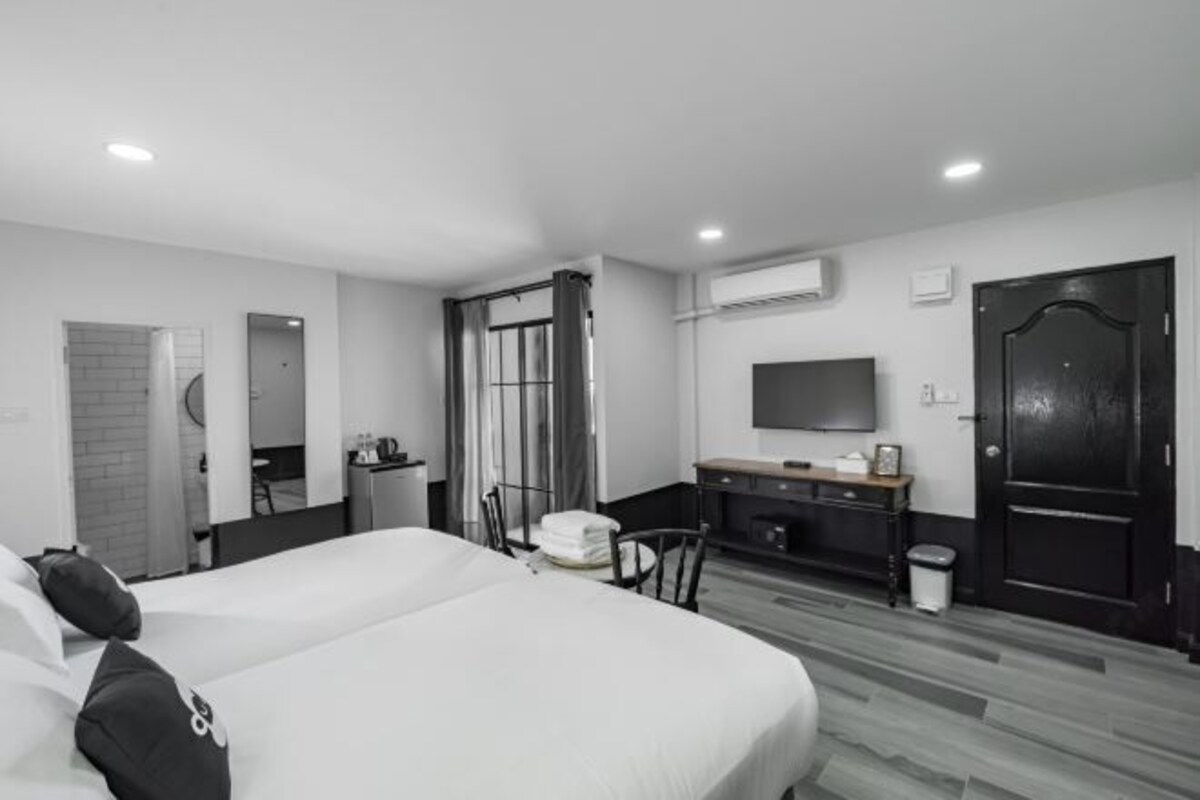 Una habitación de hotel moderna con una cama grande, un escritorio, una silla, un televisor y un armario.