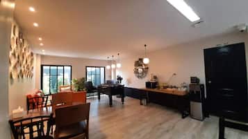 A spacious living area with a dining table, chairs, a sofa, and a kitchen area with a refrigerator and microwave.