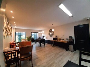 A spacious living area with a dining table, chairs, a sofa, and a kitchen area with a refrigerator and microwave.