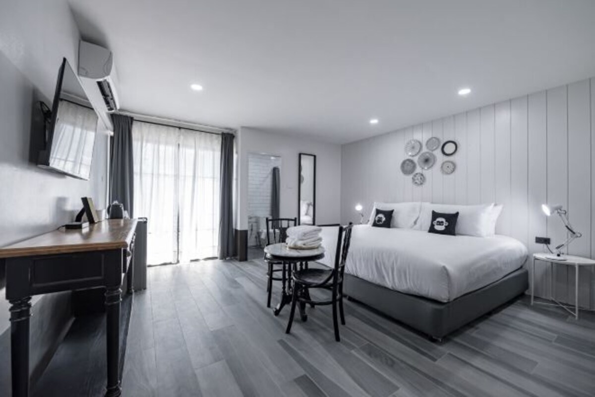 Una habitación de hotel moderna con una cama grande, un escritorio y una silla.