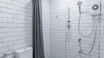 A modern bathroom with white subway tiles, a toilet, a shower area, and a towel rack.