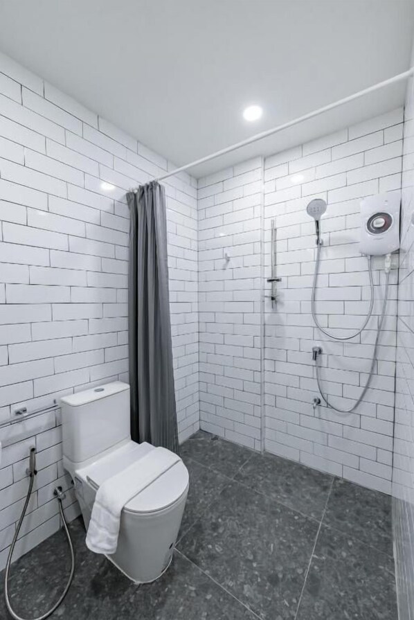 A modern bathroom with white subway tiles, a toilet, a shower area, and a towel rack.