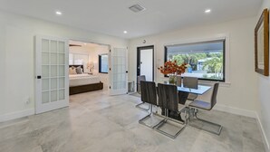 Ein modernes Interieur mit Essbereich, einem Bett und Blick durch ein Fenster.