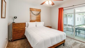 A bedroom with a bed, wooden dresser, ceiling fan, and a view of the outside through a sliding glass door. - Mid-Century Gainesville Getaway: 3 Mi to UF Campus (Gainesville)