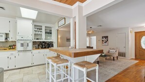 Eine moderne Küche mit weißen Schränken, einer Holz Arbeitsplatte und drei Barhocker.