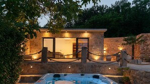 A hot tub in front of a stone building with a glass door and a chain barrier. - Villa Mia 2 (Podbablje)