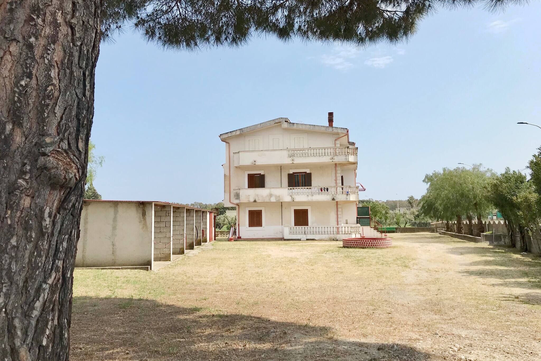 A two-story building with a balcony, a small front porch, and a paved driveway.